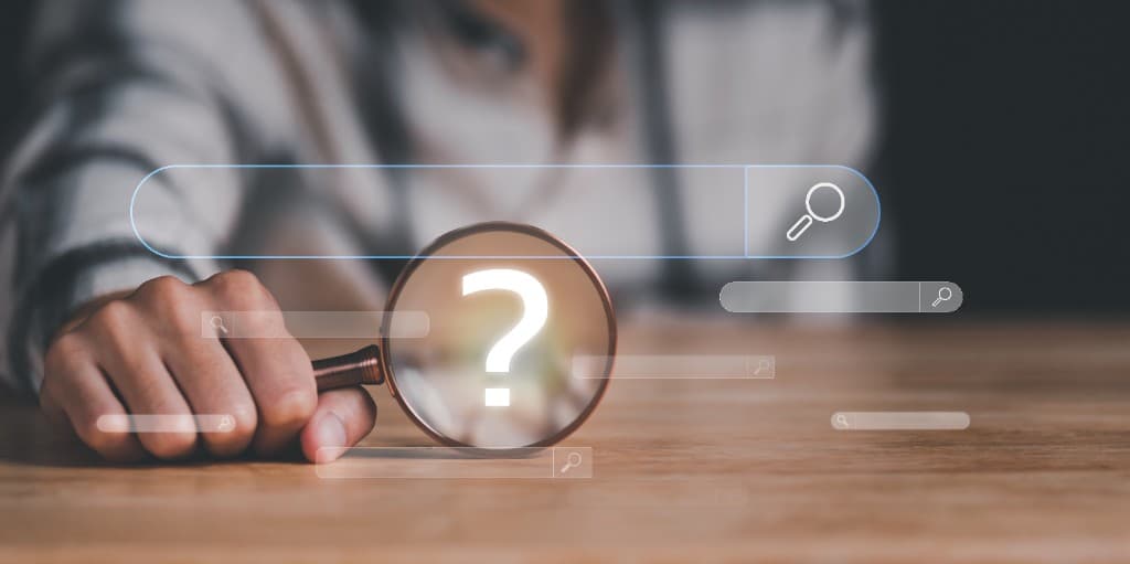 Hand holding a magnifying glass over a search bar with a question mark